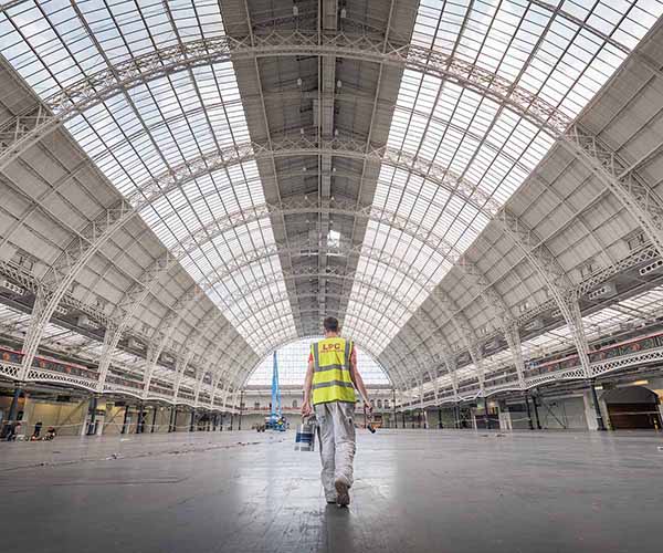 Professional painter and decorator walking with a paint tin in a large hall