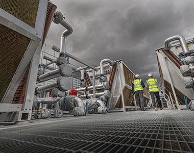 Two workers on the roof of a building inspecting plant machinery