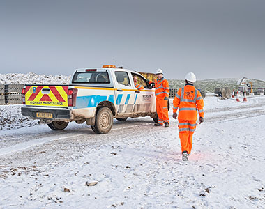 Construction workers in orange Hi-Viz on a snowy road